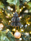 Decorative Christmas tree ornament hanging on a Christmas tree with blurred lights in the background.