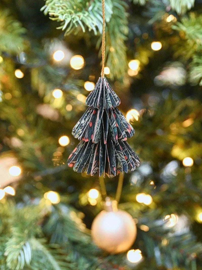 Decorative Christmas tree ornament hanging on a Christmas tree with blurred lights in the background.