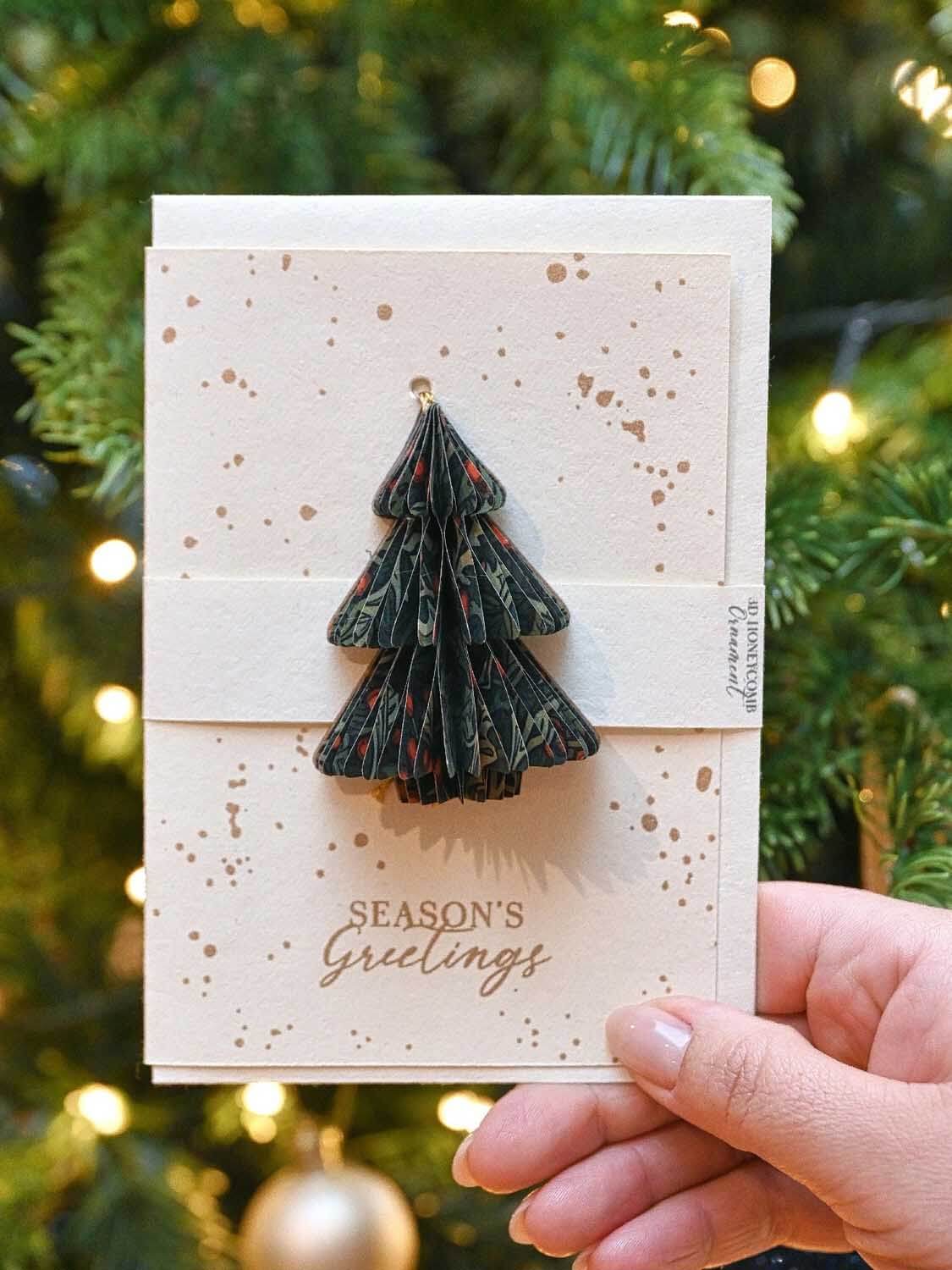 A Christmas card with a honeycomb tree ornament against a festive background