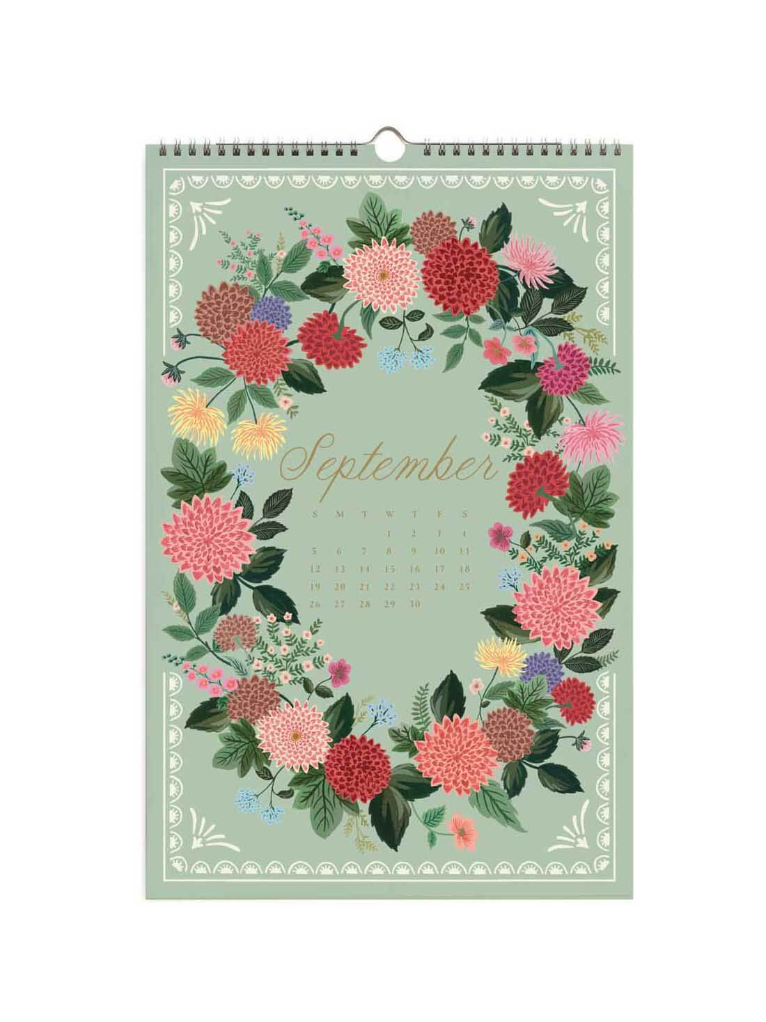 A hanging September wall calendar featuring a pastel green cover decorated with a colorful floral wreath and the word 'September' in gold script.