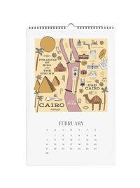 A spiral-bound February desk calendar featuring a beige illustrated map of Cairo with landmarks and text, plus a printed calendar grid below on a white page.