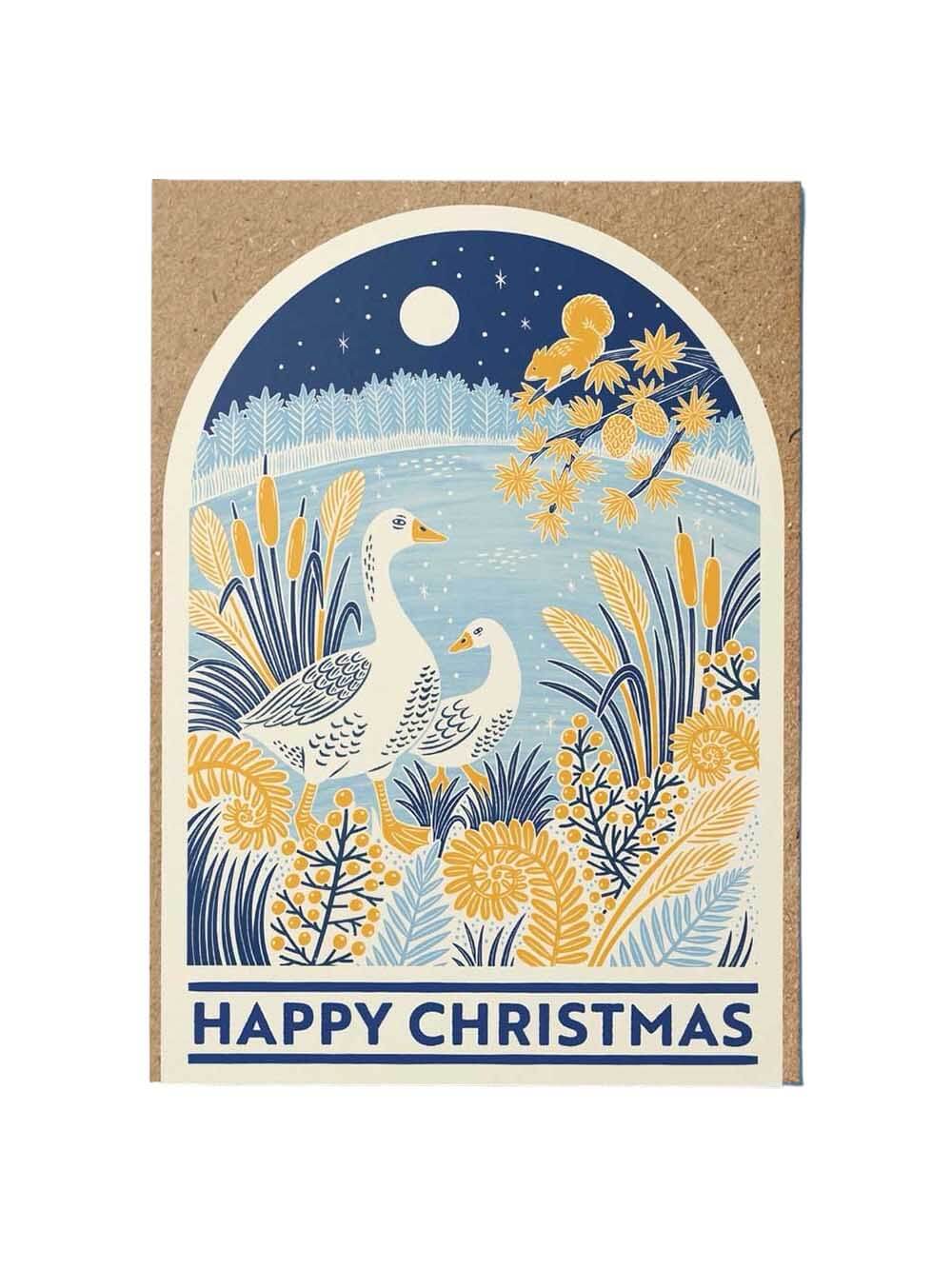 A Christmas-themed kraft paper gift tag or card featuring an illustrated winter landscape with two white geese among yellow flowers and blue reeds under a starry night sky, with the text 'HAPPY CHRISTMAS' at the bottom.