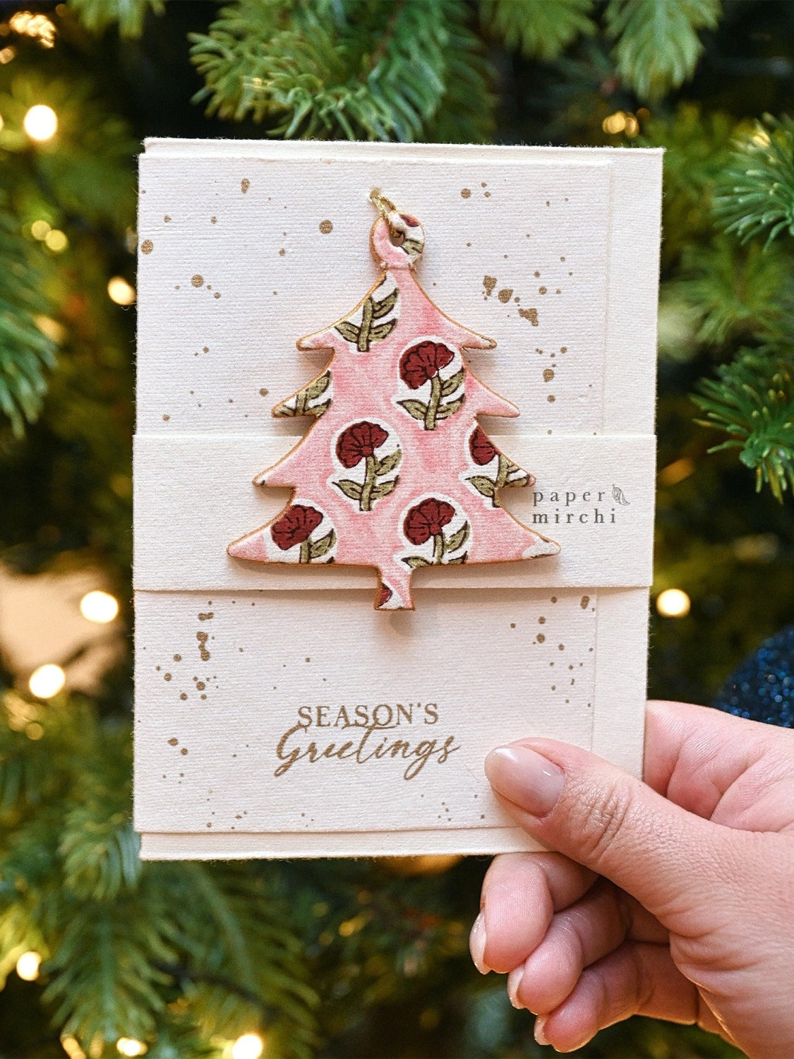 A Christmas card with a pink tree design against a festive background